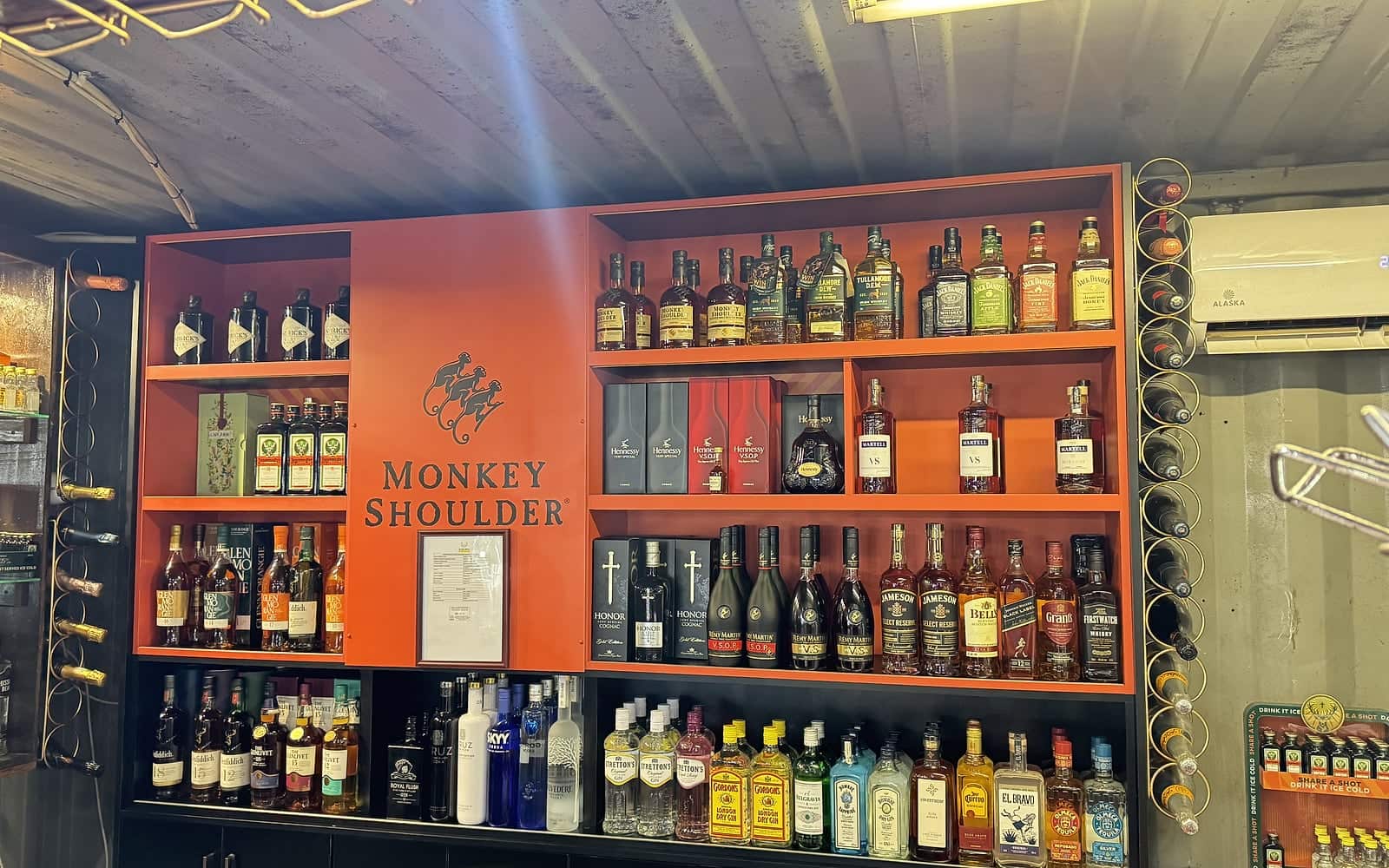 The stocked back bar at Zaba's — whisky, cognac, gin and vodka on orange shelves around a Monkey Shoulder display
