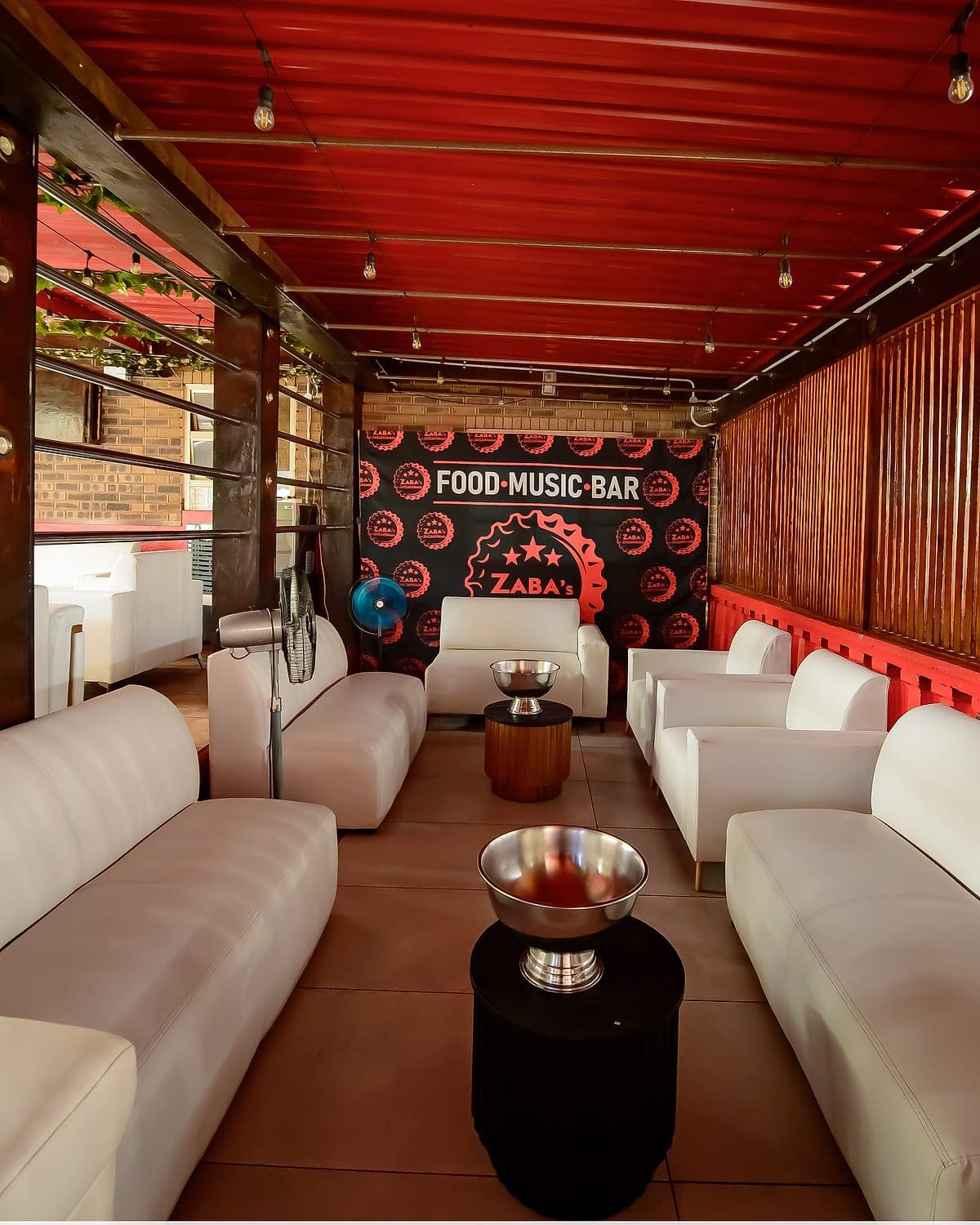 White leather couches facing the Food, Music, Bar backdrop at Zaba's