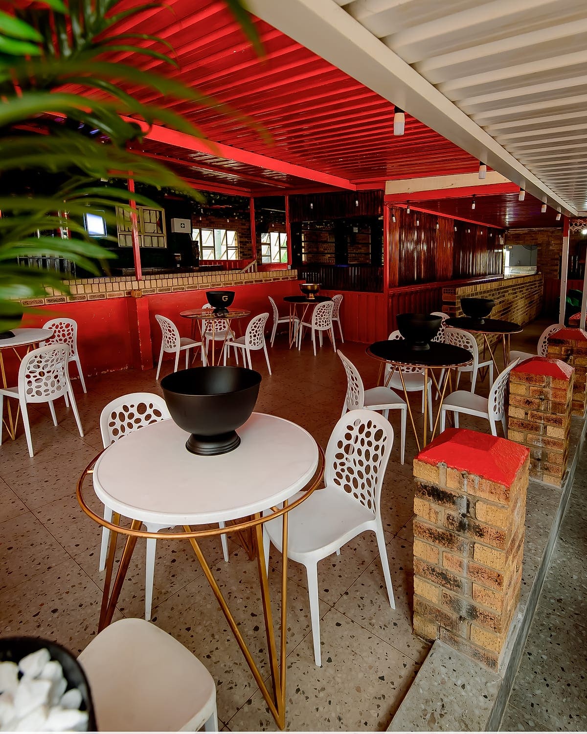 Tables and chairs set out under the red roof at Zaba's, with the bar behind them