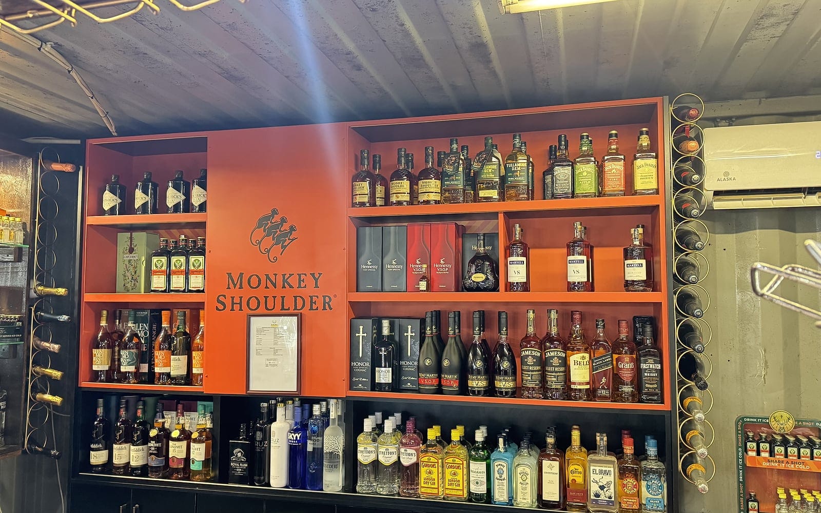 The stocked back bar at Zaba's — whisky, cognac, gin and vodka on orange shelves around a Monkey Shoulder display