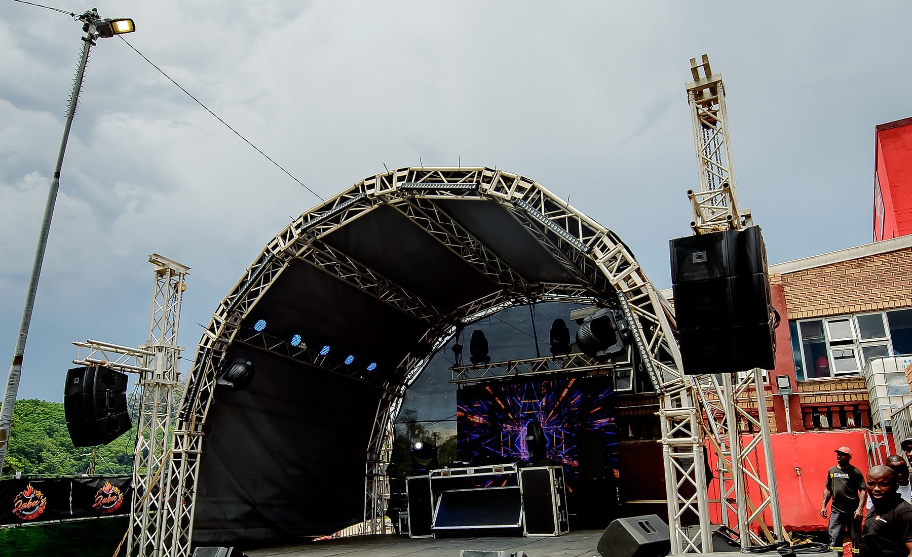 A full concert stage with truss roof, line-array speakers and LED wall set up in the yard at Zaba's Shisanyama