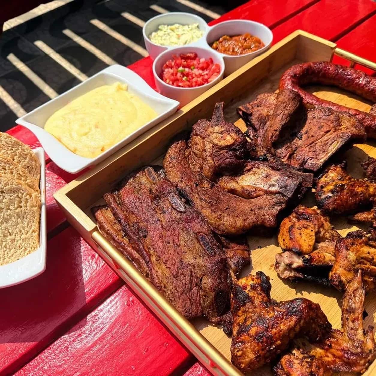 Flame-grilled lamb chops with steamed pap and chilli relish on a wooden board
